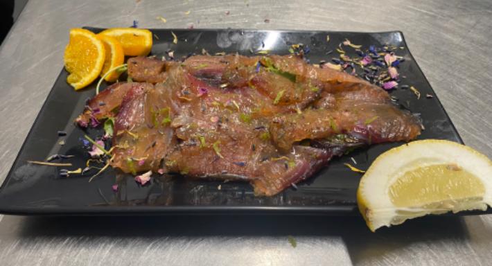 Carpaccio su ardesia nera, con spicchi d'arancia, limone e petali essiccati