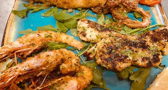 Gamberi panati e pesce alla griglia su un piatto turchese, con la rucola