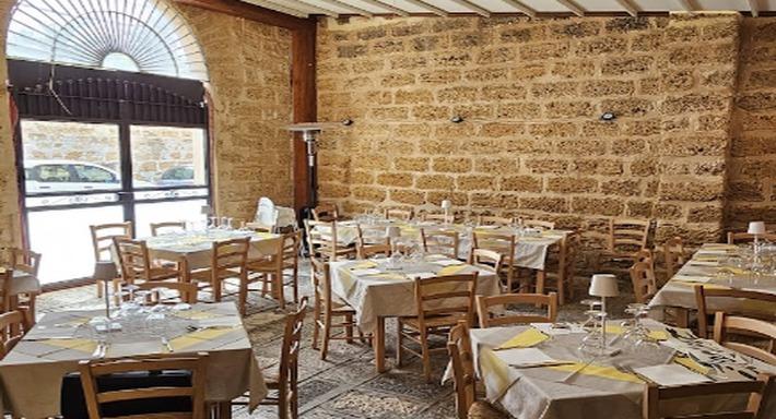 La sala verso l'arco che dà sulla strada, muro di tufo, sedie di legno chiaro e pavimento a cementine