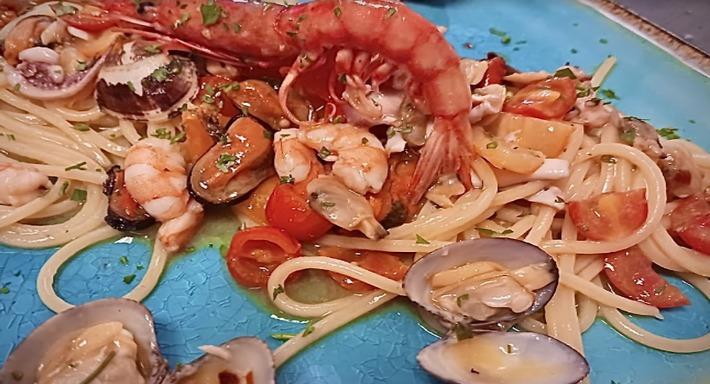 Spaghetti con cozze, vongole, gamberi e pomodorini su un piatto turchese